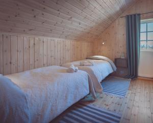 twee bedden in een kamer met houten wanden en houten vloeren bij Vengsøy Rorbuer in Vengsøya