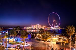 a city with a ferris wheel at night at HOMESTAR, Deluxe Hostel - JBR - Walk To Beach, Metro Station in Dubai