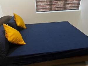- un lit avec des oreillers jaunes au-dessus dans l'établissement Canterbury Residence Garden Apartments, à Kahatuduwa