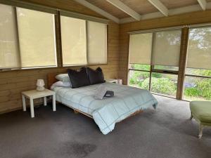 a bedroom with a bed in a room with windows at Patsy's Gate - Red Hill South in Red Hill South