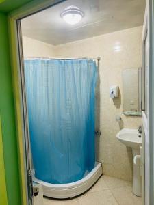 a bathroom with a shower with a blue shower curtain at Villa Jakos Paradise in Batumi