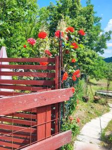 een houten bank naast een hek met rode bloemen bij Apartment Julijana in Koper