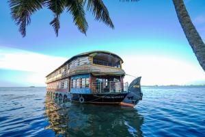 a boat sitting in the water next to a palm tree at Venice Premium Houseboats Alleppey in Alleppey