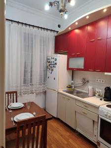 cocina con armarios rojos, mesa y nevera en Red cross 58 apartment, en Vračar (historical)