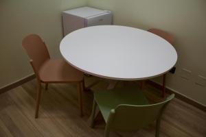 een witte tafel en stoelen in een kamer met een koelkast bij H2ome Bolzaneto in Genua
