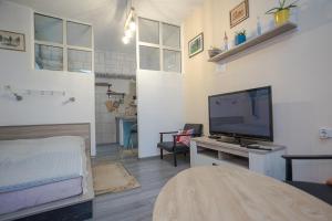 a living room with a flat screen tv and a bed at Studio apartman Kamenčić in Osijek