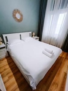 Schlafzimmer mit einem Bett mit weißer Bettwäsche und einem Spiegel in der Unterkunft Fly Residence in Arad