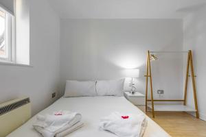 una camera da letto con un letto bianco e asciugamani di 2-BR London Oasis in Woolwich a Londra