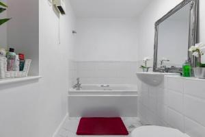 a white bathroom with a tub and a red rug at 2-BR London Oasis in Woolwich in London