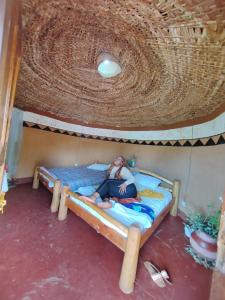 a woman sitting on a bed in a play house at Rock garden Sipi in Kapchorwa