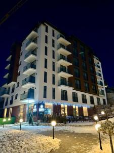 a large white building in the snow at night at Harmonija Resort - Harmonia Palace in Kopaonik