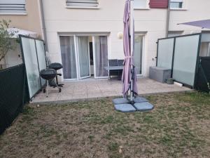 un paraguas sentado en el césped en un patio en Duplex avec terrasse et jardin en Dammarie-lès-Lys