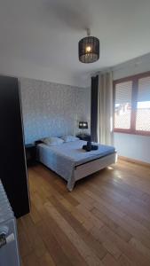 a bedroom with a bed and a wooden floor at Chambre Luxurieux Gris in Perpignan
