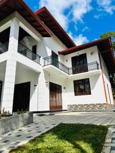 ein weißes Haus mit schwarzen Fenstern und Balkonen in der Unterkunft The Kandyan Secret Villa - Free Pick up From Kandy Railway Station in Kandy
