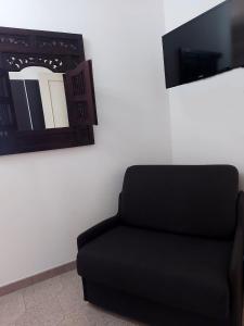 ein schwarzer Stuhl neben einer Wand mit einem Spiegel in der Unterkunft B&B Acchiappasogni in Corigliano dʼOtranto
