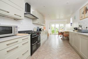 a kitchen with white cabinets and a stove top oven at The Sea House Beautiful Large Whitstable Home With Sea Views in Kent