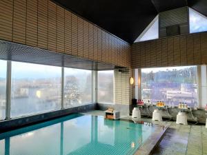 a swimming pool in a building with large windows at Itoen Hotel Asamanoyu in Matsumoto