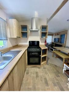 a kitchen with a sink and a stove at Janet's Beautiful Country Caravan in Pwllheli