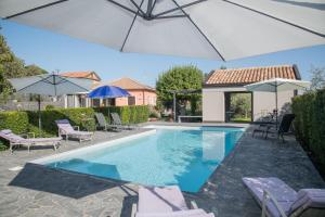 a swimming pool with chairs and umbrellas in a yard at La Casa dell'Alloro in Zafferana Etnea