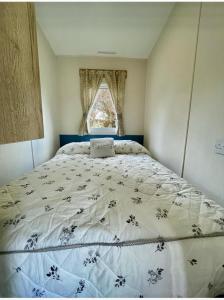 a large bed in a room with a window at Janet's Beautiful Country Caravan in Pwllheli