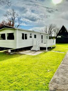 a white mobile home on a grass field at Janet's Beautiful Country Caravan in Pwllheli