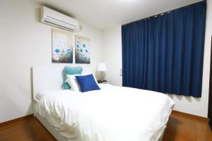 a bedroom with a white bed and blue curtains at 錦糸町 in Tokyo