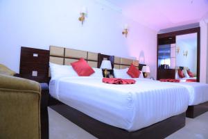 a bedroom with two large beds with red pillows at Sunland International Hotel in Addis Ababa