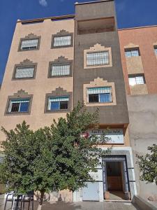 un grand bâtiment avec un arbre devant lui dans l'établissement Residence El Oukhowa, à Ouarzazate