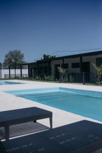 a swimming pool with a bench in front of a building at Vento Hotel in María Grande