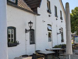 Hotel Restaurant Roerdalen في Posterholt: فناء في الهواء الطلق مع طاولات وكراسي ومبنى