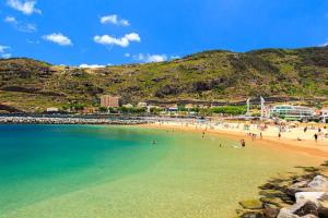 a beach with a bunch of people in the water at Machico center w/ terrace 5 min beach in Machico