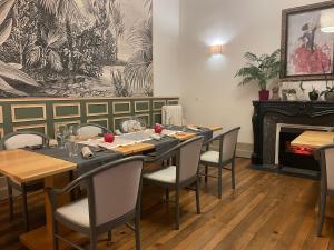een eetkamer met een tafel en stoelen en een open haard bij Le St Vincent in Roquefort