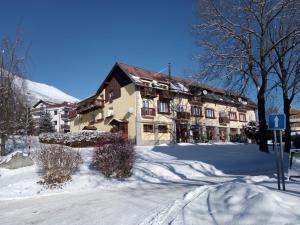 a building with snow on the ground next to a street at Tatranská garsónka in Vysoke Tatry - Novy Smokovec