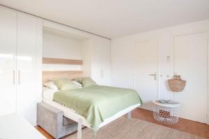 a white bedroom with a bed and a table at Studio vue mer climatisé à 100m des plages in Saint-Jean-Cap-Ferrat