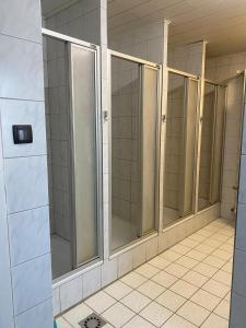 a row of glass shower stalls in a bathroom at Einfache Schlafmöglichkeit mit Gemeinschaftsküche und Bad in Brombachtal