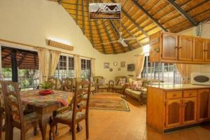 a kitchen and living room with a table and chairs at Nag-Apie Vakansiehuis in Marloth Park