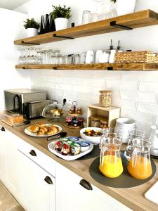a kitchen counter with plates of food and orange juice at Logis de L'Arceau in Celles