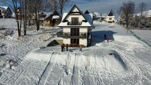 a group of people standing in the snow in front of a house at Leszczyniański Domek in Biały Dunajec