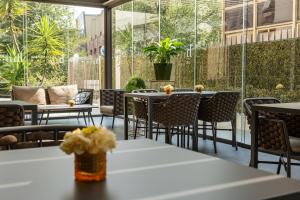 an outdoor patio with tables and chairs and windows at Helios Hotel & Restaurant in Monza