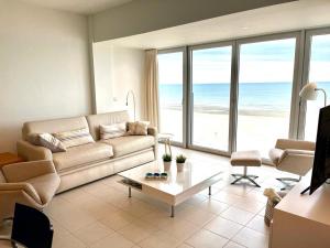 a living room with a couch and a view of the ocean at Zeedijk Koksijde in Koksijde