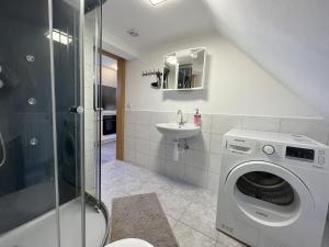 a bathroom with a washing machine and a sink at Gasthaus Katrin in Königslutter am Elm