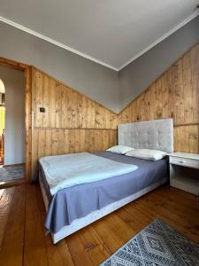 ヤレムチャにあるSadyba Girske Povitriaの大きなベッドと木製の壁が備わるベッドルーム1室が備わります。