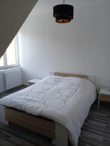 a bedroom with a bed with a white comforter at location maison vacance in Pouru-Saint-Rémy