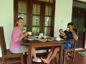 kobieta i mężczyzna siedzący przy stole z dzieckiem w obiekcie Nature Lodge w mieście Sigirija