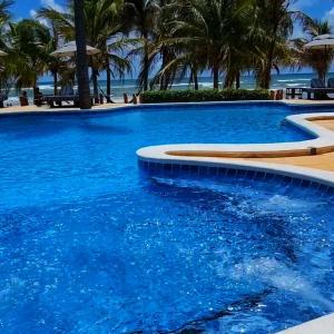 a large swimming pool with blue water and palm trees at Hotel Rede Beach in Trairi