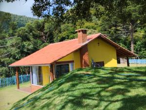 a small yellow house with a red roof at Chalé Mirante Da Guapiara in Aiuruoca