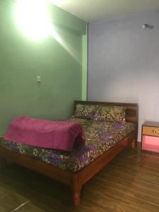 a bedroom with a bed with a purple blanket on it at Little Heaven Restaurant & Guesthouse in Deorāli