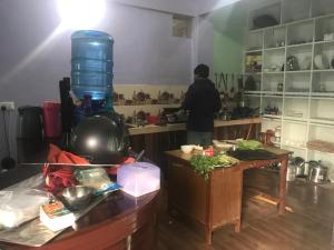 un homme debout dans une cuisine préparant la nourriture dans l'établissement Little Heaven Restaurant & Guesthouse, à Deorāli
