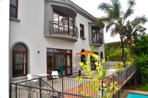 a white house with a balcony and a pool at Ambonnay Terrace Guest House in Pretoria