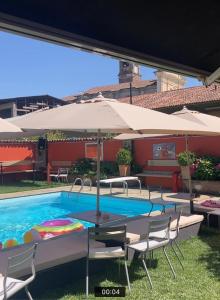 uma piscina com cadeiras e uma mesa com um guarda-sol em B&B Villa la Canonica a Padernello 